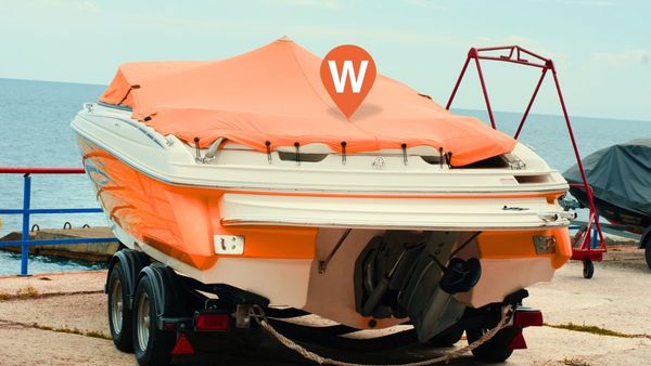 An orange and white boat by the water with a cover on it and a WhereSafe GPS logo above it.
