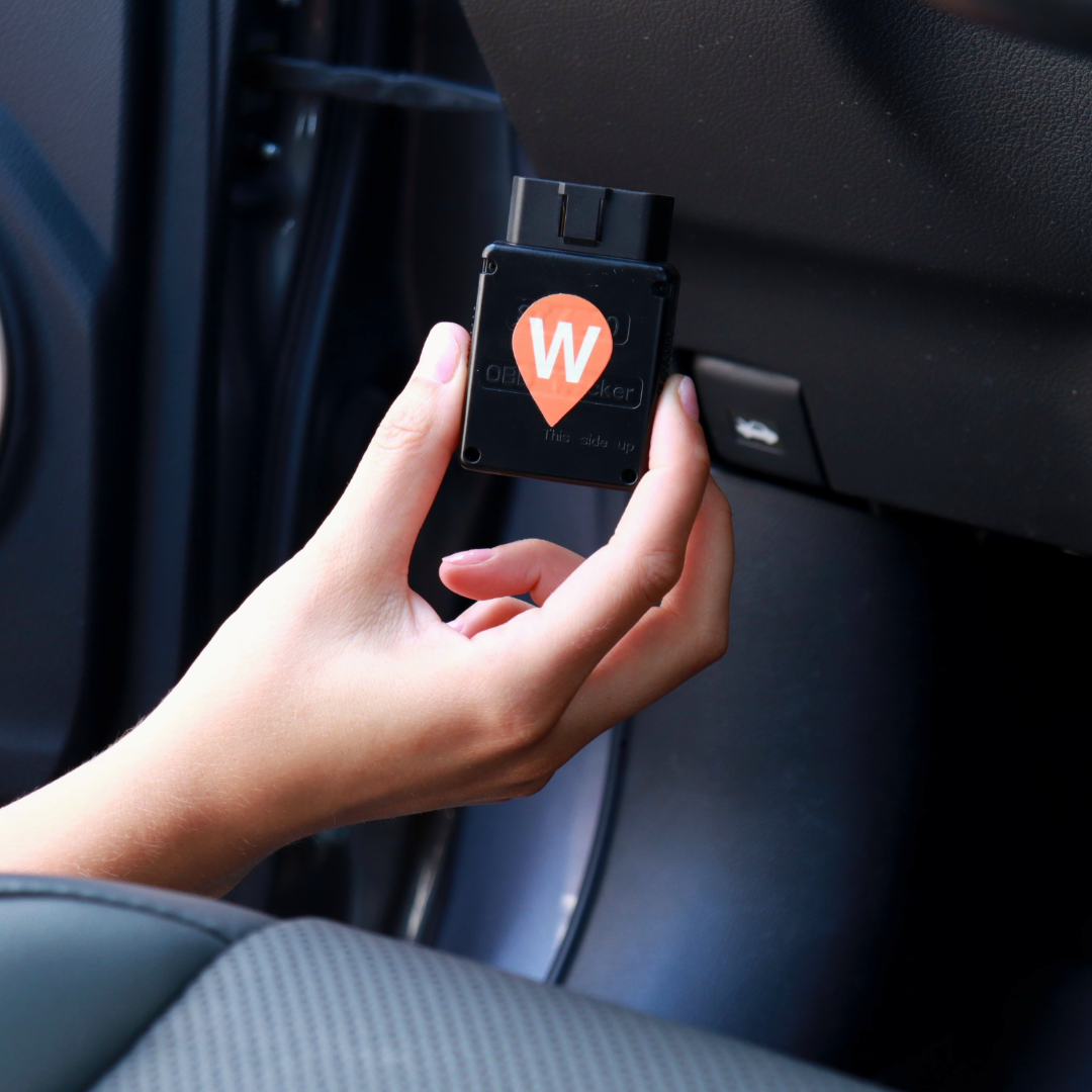 WhereSafe OBD Plug-in GPS tracker with a WhereSafe logo, being installed in a car. 